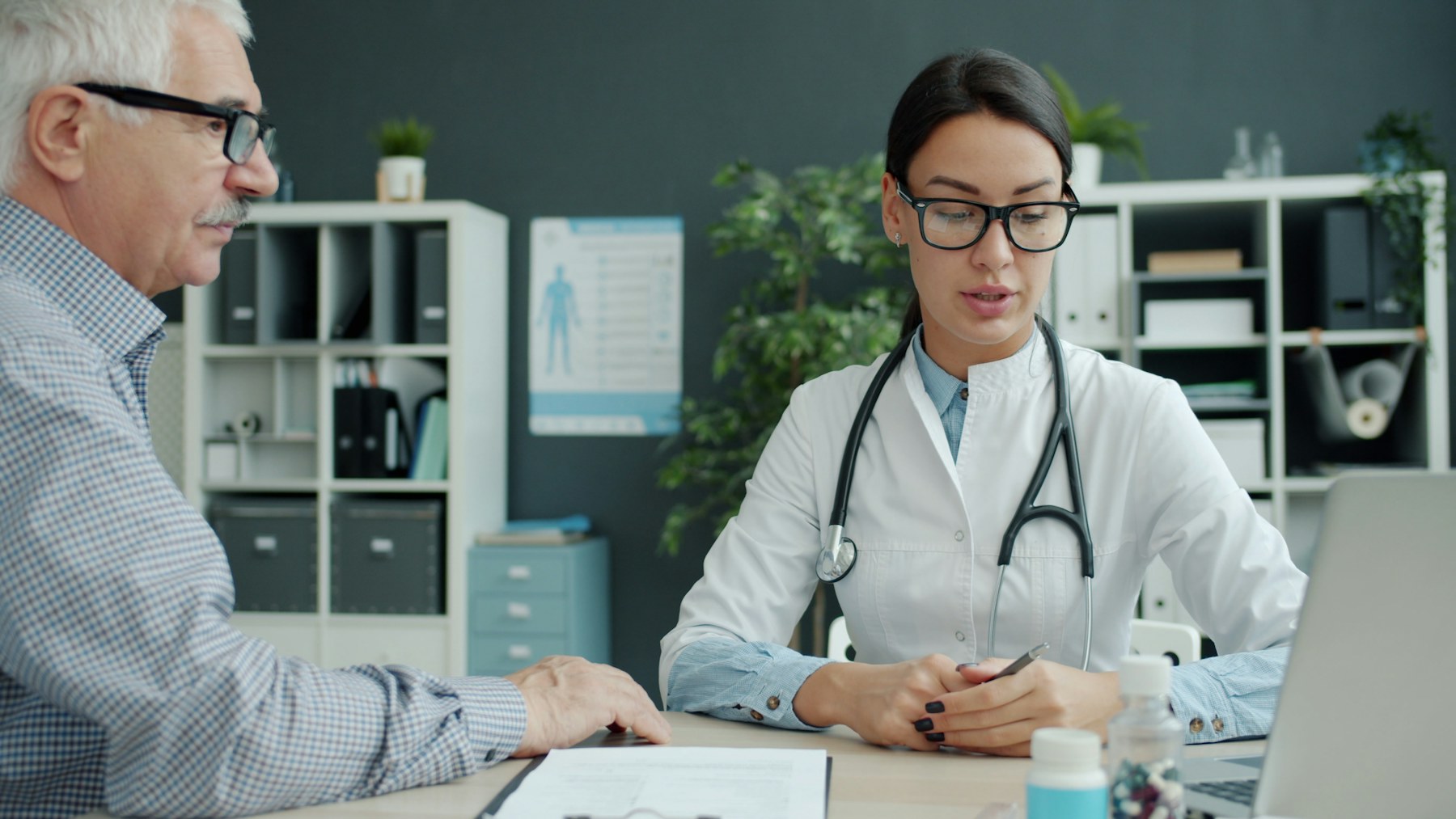 Una profesional sanitaria conversa con un paciente adulto en una consulta